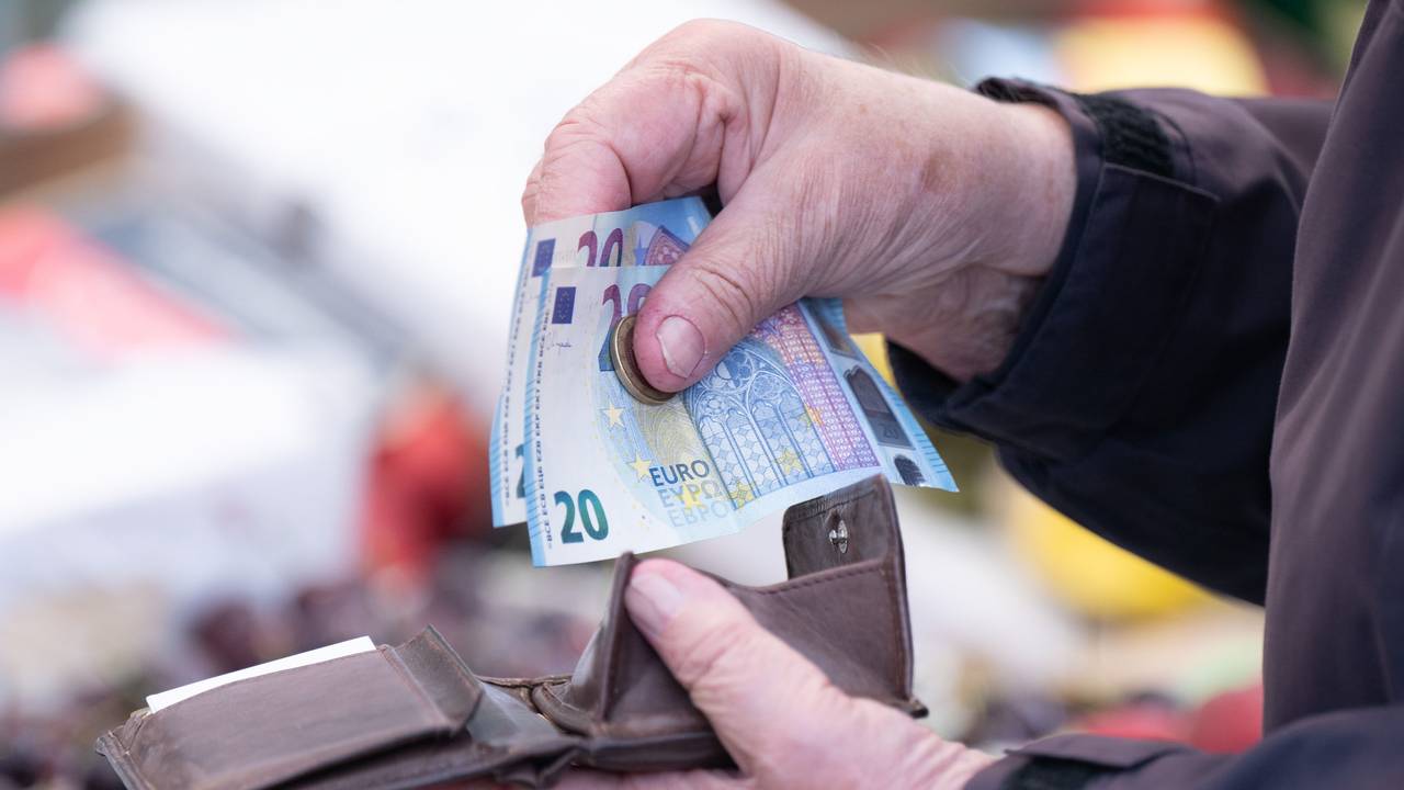 Eine Frau sortiert auf einem Wochenmarkt das Wechselgeld für ihre Einkäufe in ein Portemonnaie.