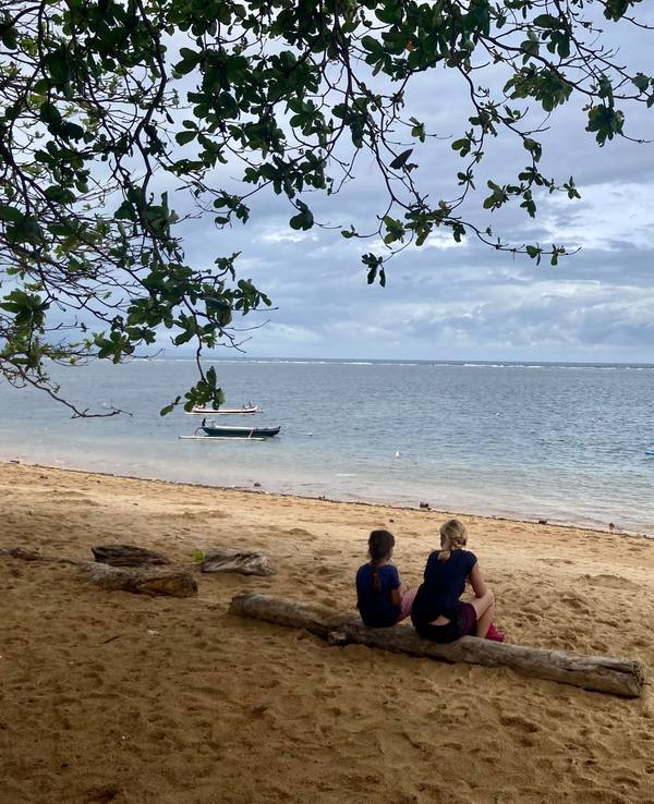 Zwei Urlauber sitzen am Strand auf der indonesischen Urlaubsinsel Bali.