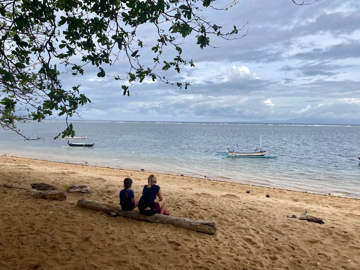 Zwei Urlauber sitzen am Strand auf der indonesischen Urlaubsinsel Bali.