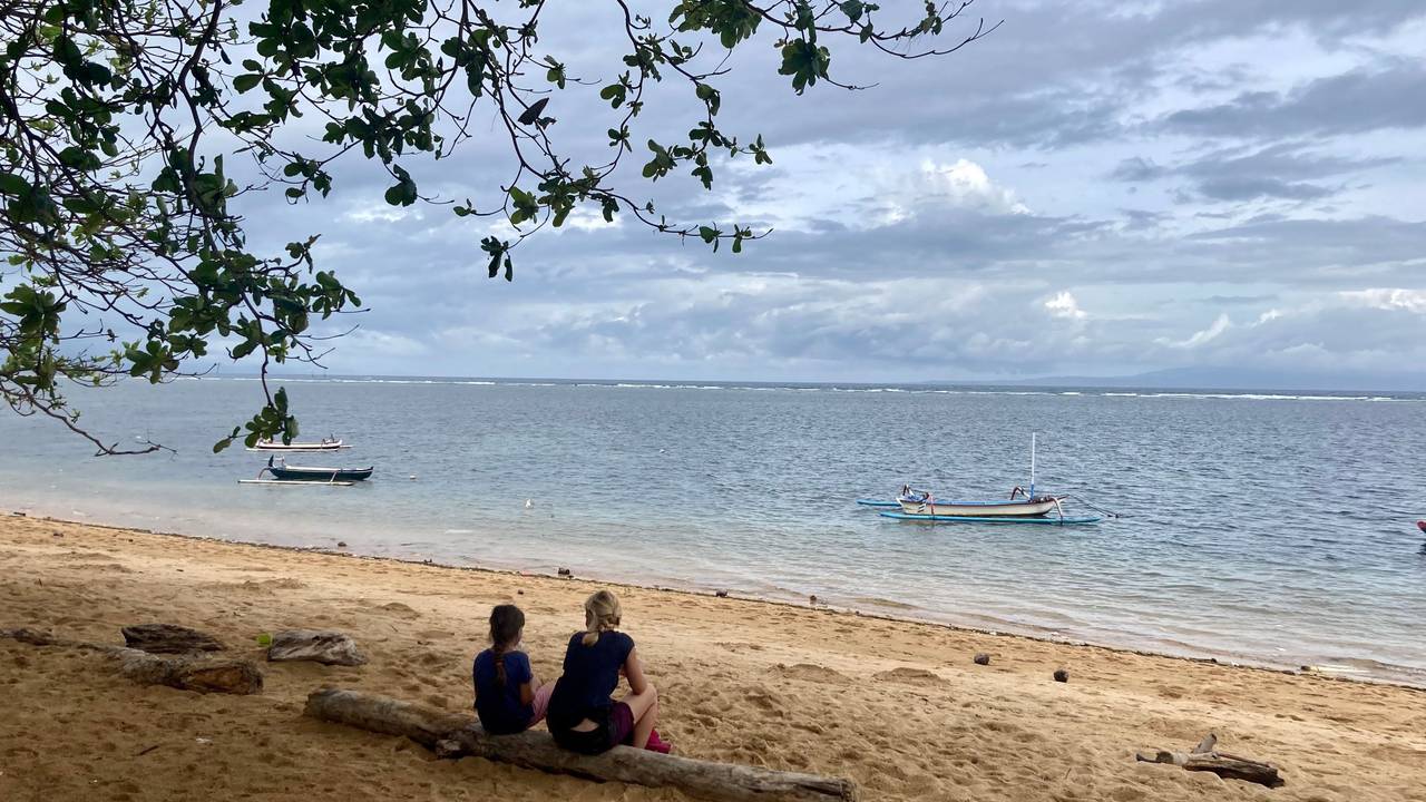 Zwei Urlauber sitzen am Strand auf der indonesischen Urlaubsinsel Bali.