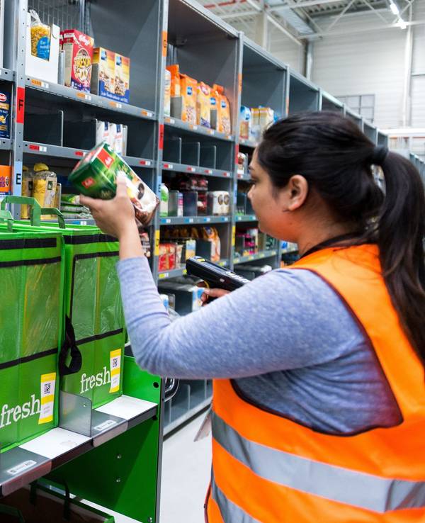 An employee of grocery delivery service Amazon Fresh scans ordered products in the company depot in Berlin, Germany, 18 July 2017. Amazon Fresh started in Berlin and Potsdam in early May, with a range of around 85,000 products. The company is now expanding its online supermarket to the northern city of Hamburg. Photo: Monika Skolimowska/dpa +++ dpa-Bildfunk +++