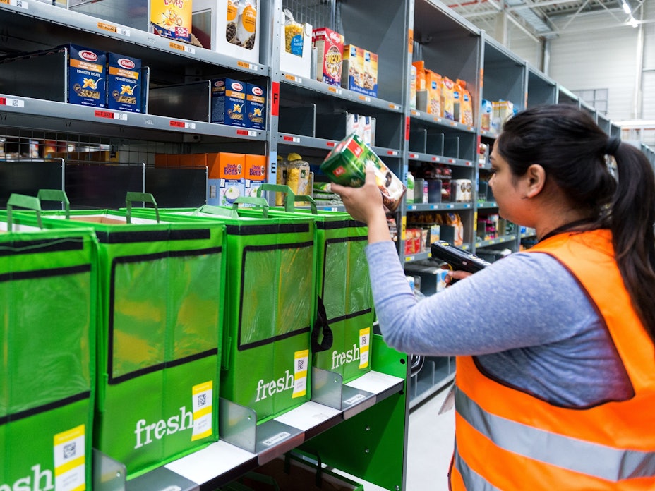 An employee of grocery delivery service Amazon Fresh scans ordered products in the company depot in Berlin, Germany, 18 July 2017. Amazon Fresh started in Berlin and Potsdam in early May, with a range of around 85,000 products. The company is now expanding its online supermarket to the northern city of Hamburg. Photo: Monika Skolimowska/dpa +++ dpa-Bildfunk +++