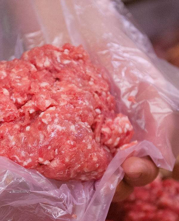 Ein Mitarbeiter eines Fleischerei-Fachgeschäfts hält eine Portion Mett in der Hand (Symbolfoto).