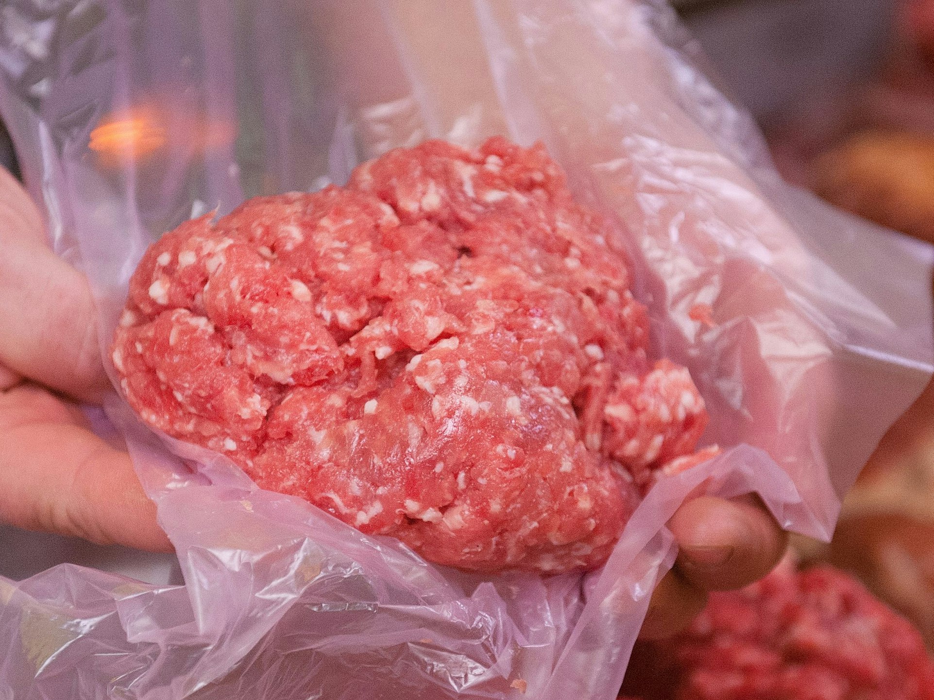 Ein Mitarbeiter eines Fleischerei-Fachgeschäfts hält eine Portion Mett in der Hand (Symbolfoto).