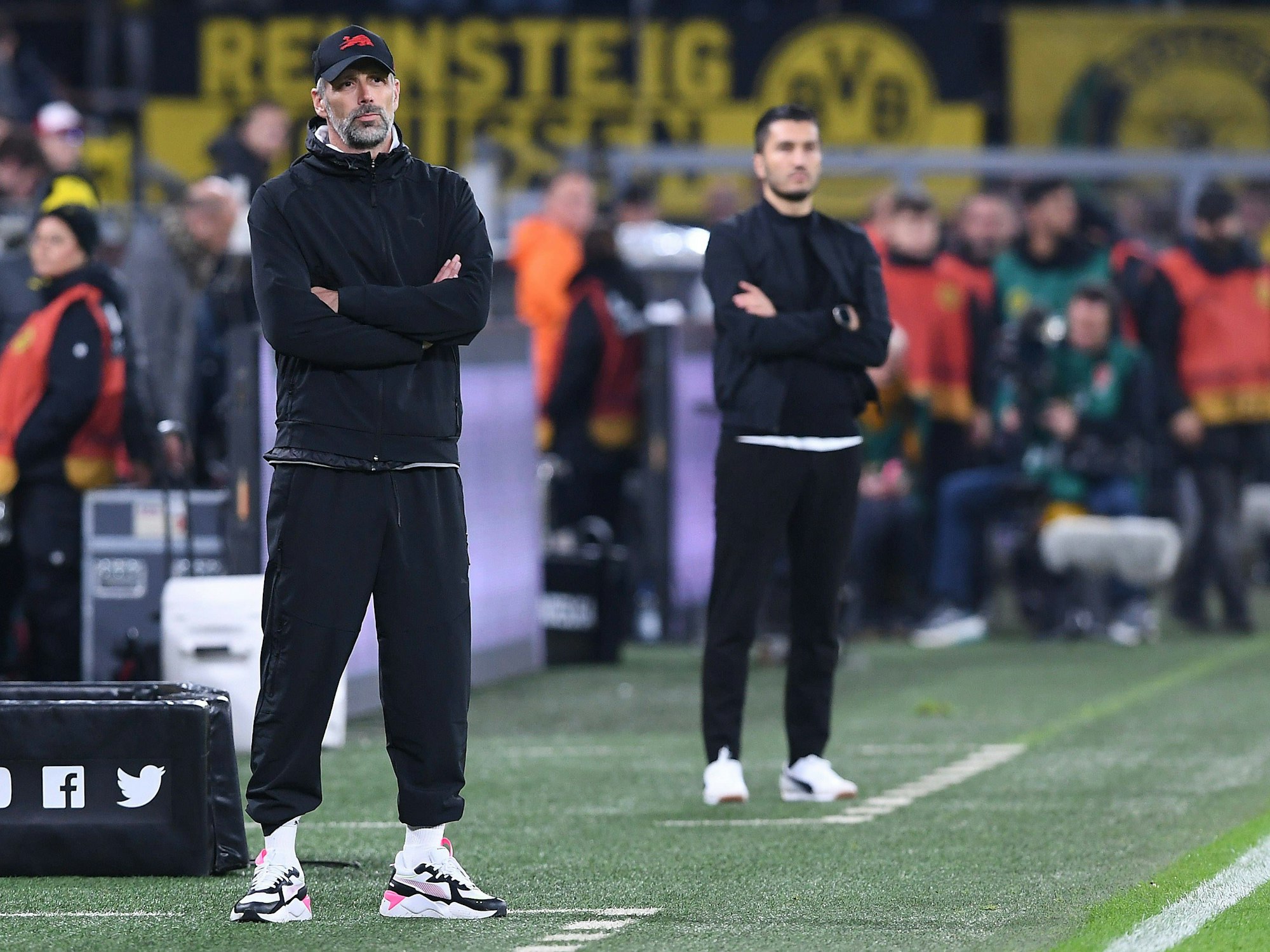 Marco Rose und Nuri Sahin stehen während des Bundesliga-Spiels Borussia Dortmund gegen RB Leipzig mit verschränkten Armen an der Seitenlinie.