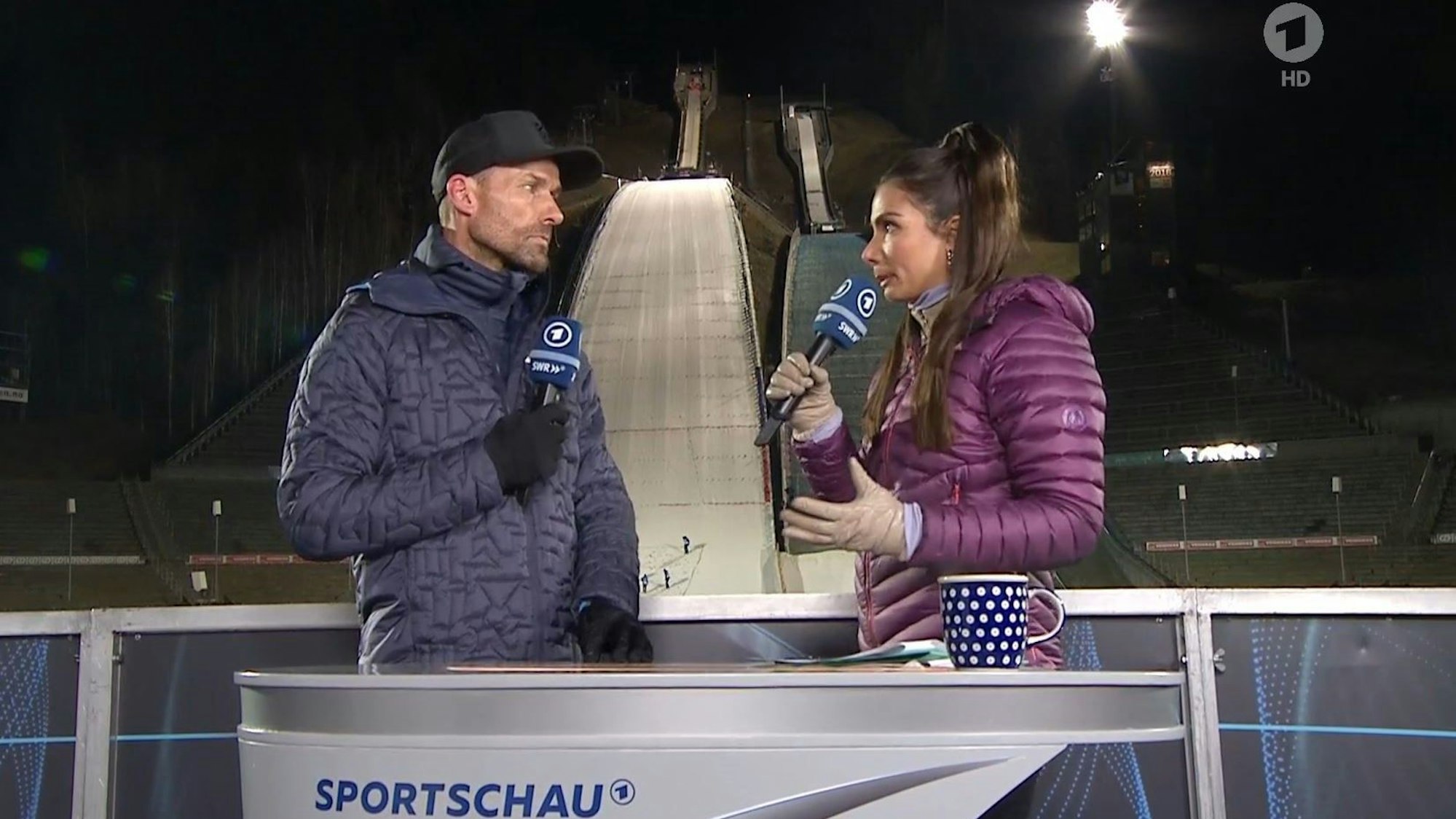 Sven Hannawald und Lea Wagner sprechen in der ARD beim Skispringen miteinander.