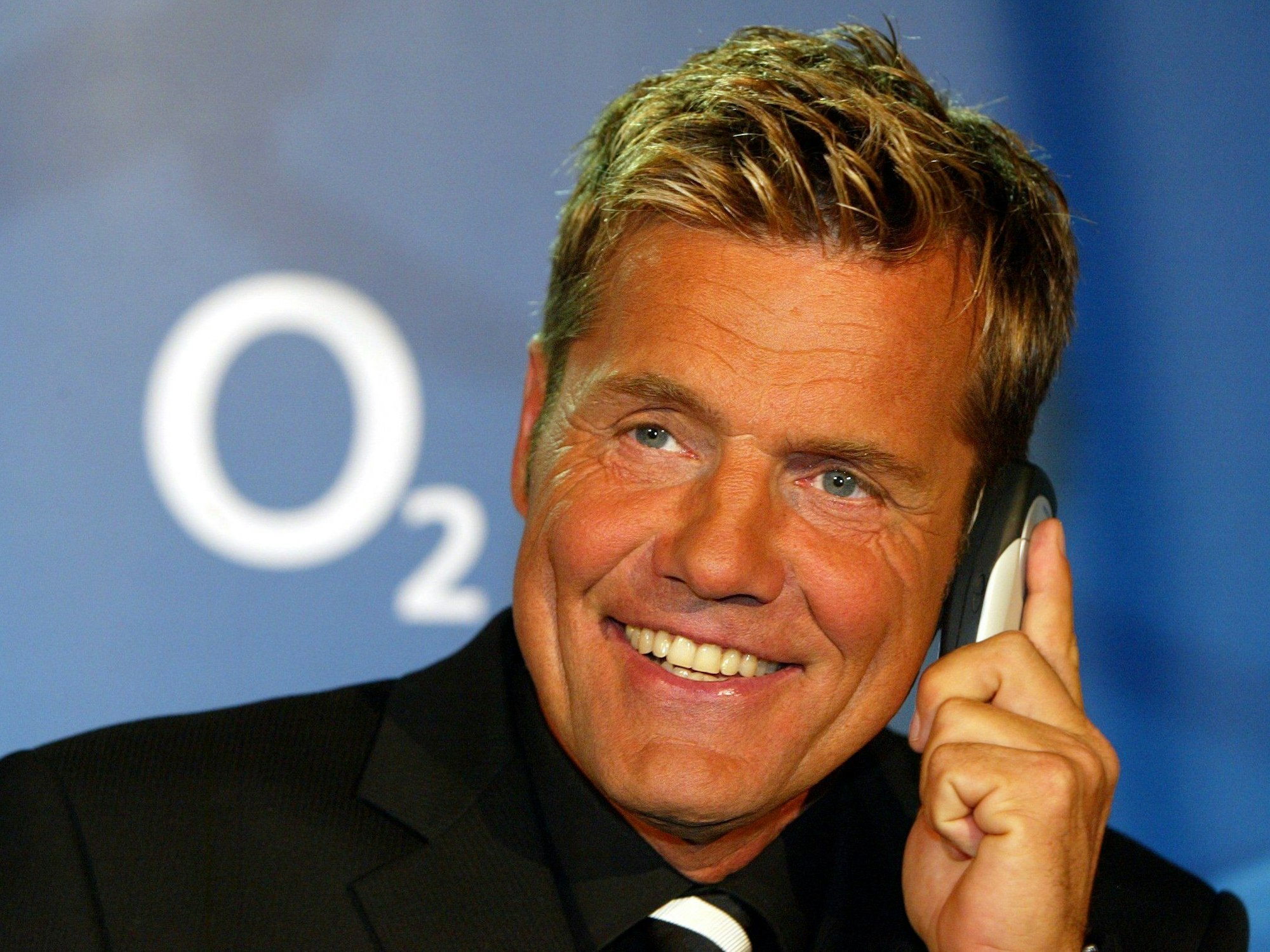Musikproduzent Dieter Bohlen hält sich am Montag (22. März 2004) bei seinem Werbepartner und Mobilfunkanbieter O2 auf der weltgrößten Computermesse CeBIT in Hannover ein Telefon an das linke Ohr.