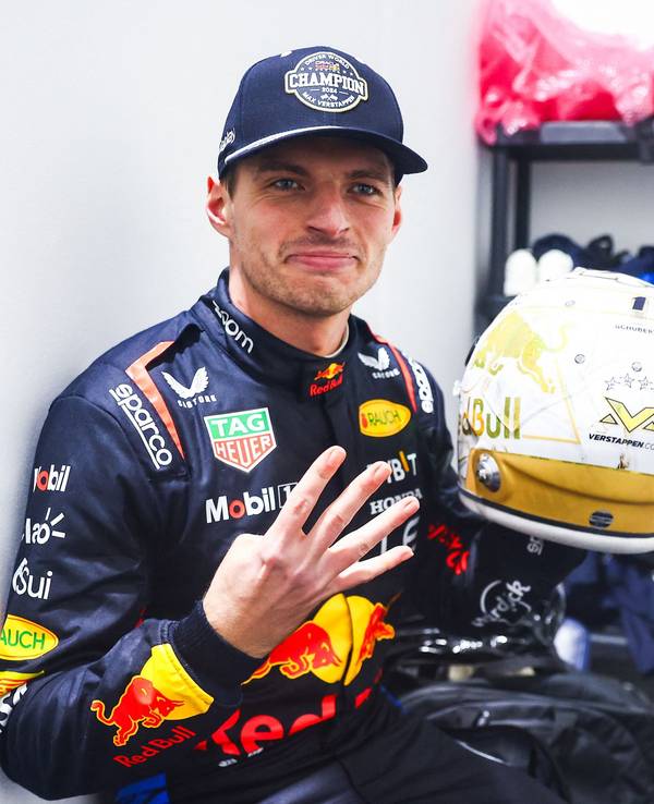 Max Verstappen zeigt vier Finger in die Kamera und hält seinen Helm.