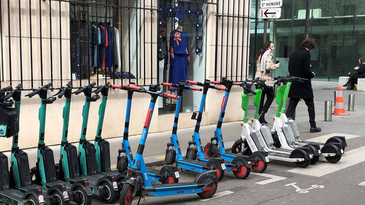 E-Scooter von drei verschiedenen Anbietern stehen auf einem dafür vorgesehenen Parkplatz.