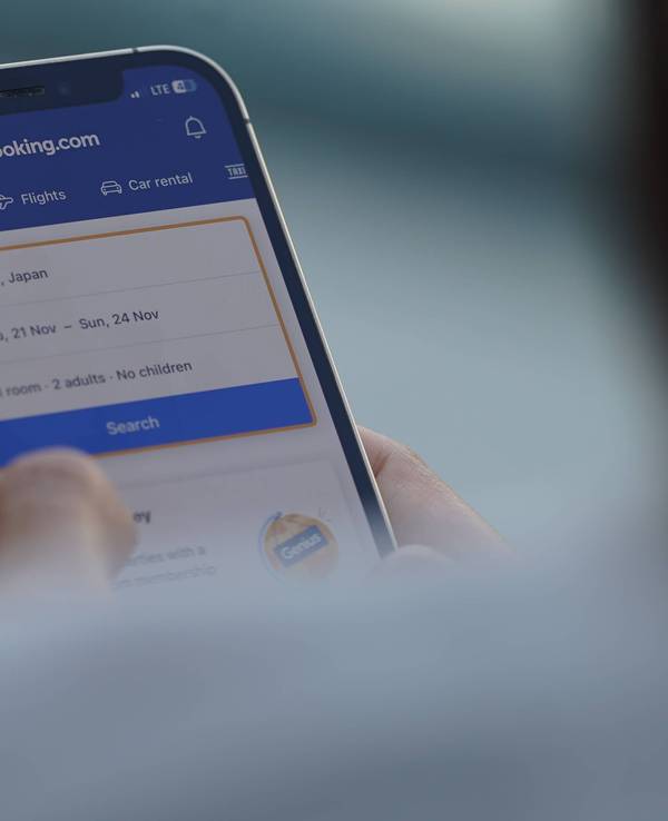 A woman browses The booking.com app to check flight and hotel prices