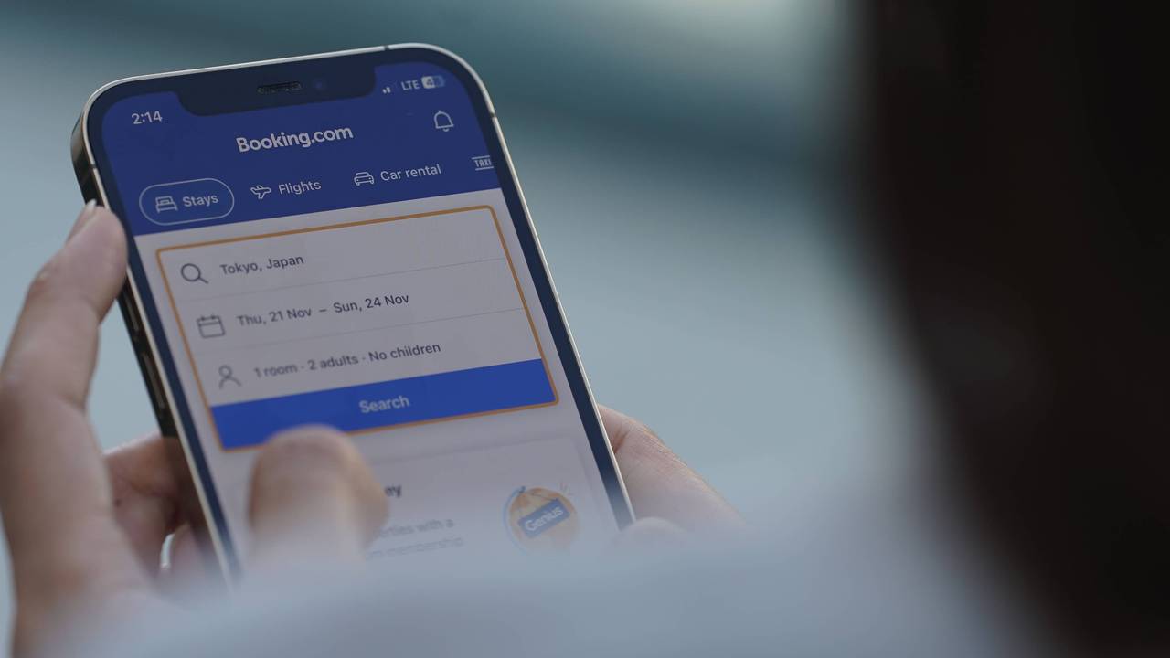 A woman browses The booking.com app to check flight and hotel prices