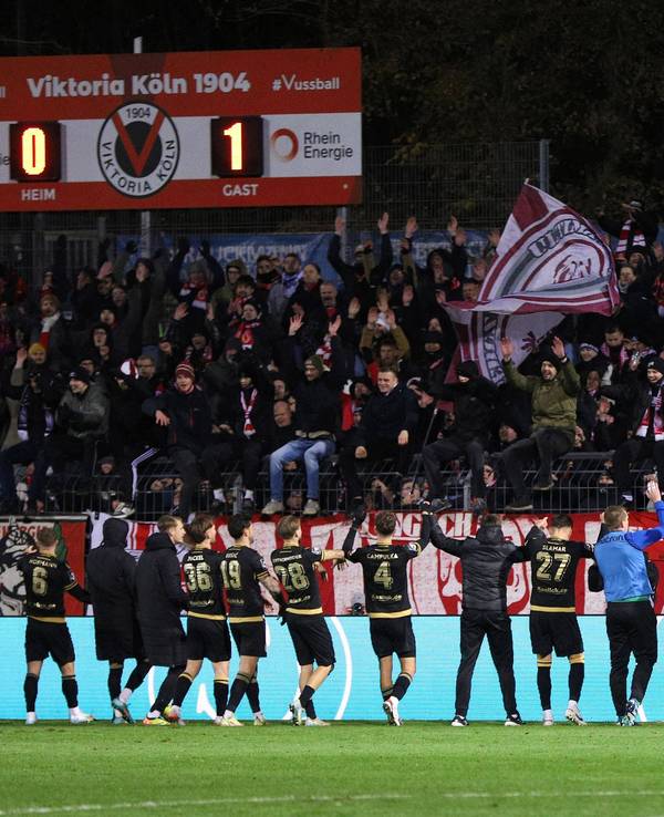 Die Mannschaft von Energie Cottbus feiert zusammen mit seinen mitgereisten Fans den Auswärtssieg beim FC Viktoria Köln am Freitagabend (22. November 2024).