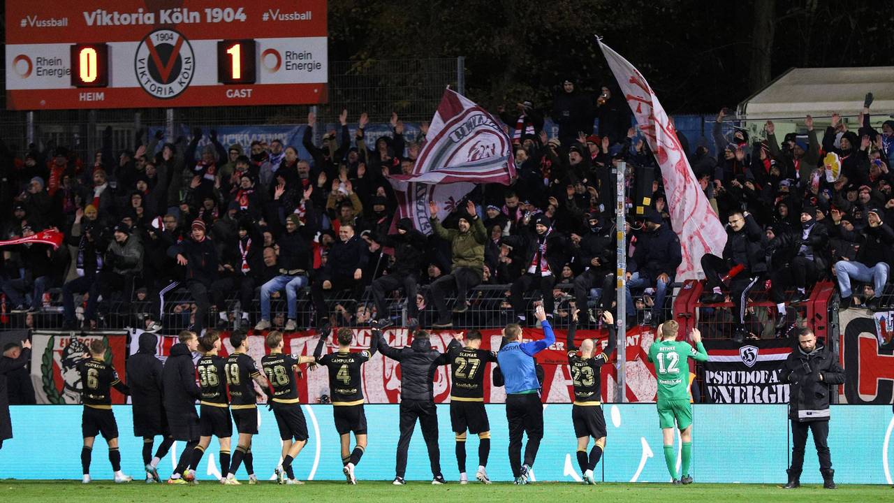 Die Mannschaft von Energie Cottbus feiert zusammen mit seinen mitgereisten Fans den Auswärtssieg beim FC Viktoria Köln am Freitagabend (22. November 2024).