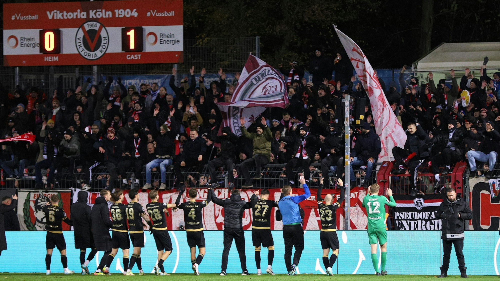Die Mannschaft von Energie Cottbus feiert zusammen mit seinen mitgereisten Fans den Auswärtssieg beim FC Viktoria Köln am Freitagabend (22. November 2024).
