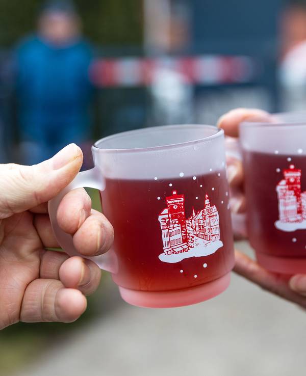 Menschen halten beim traditionellen Weihnachtsbaumweitwurf bei der Ströbitzer Feuerwehr Tassen mit Glühwein in den Händen und wärmen sich daran. Am Wettbewerb im Cottbuser Ortsteil Ströbitz, bei dem gewinnt, wer einen Weihnachtsbaum am weitesten werfen kann, nahmen mehr als 80 Besucher teil. Vorher konnten sie sich, gemeinsam mit anderen Besuchern beim Essen stärken. Der Erlös der Veranstaltung wird einer sozialen Einrichtung in der Stadt Cottbus gespendet. (zu dpa: «Viele Glühweine verstoßen gegen Kennzeichnungsvorgaben») +++ dpa-Bildfunk +++