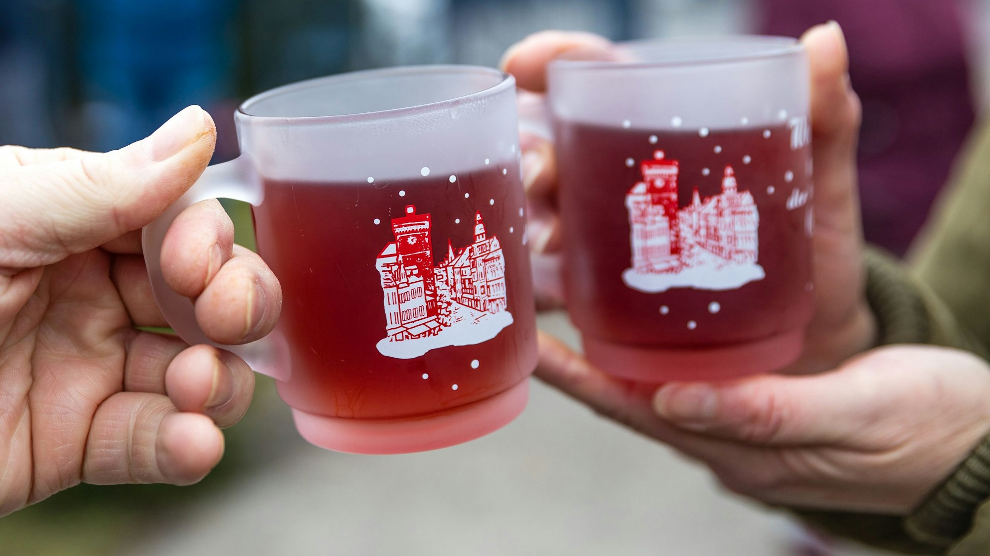 Menschen halten beim traditionellen Weihnachtsbaumweitwurf bei der Ströbitzer Feuerwehr Tassen mit Glühwein in den Händen und wärmen sich daran. Am Wettbewerb im Cottbuser Ortsteil Ströbitz, bei dem gewinnt, wer einen Weihnachtsbaum am weitesten werfen kann, nahmen mehr als 80 Besucher teil. Vorher konnten sie sich, gemeinsam mit anderen Besuchern beim Essen stärken. Der Erlös der Veranstaltung wird einer sozialen Einrichtung in der Stadt Cottbus gespendet. (zu dpa: «Viele Glühweine verstoßen gegen Kennzeichnungsvorgaben») +++ dpa-Bildfunk +++