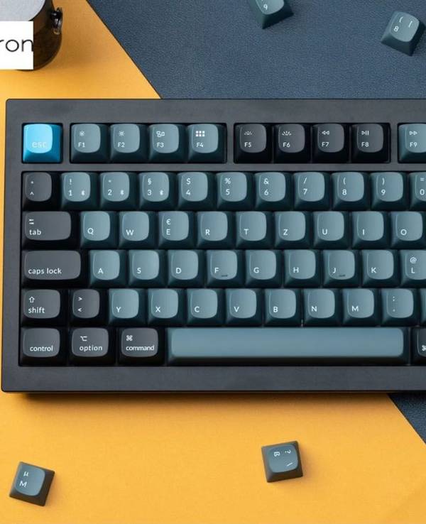 Mechanische Keychron Tastatur von oben auf gelb schwarzem Tisch mit herumliegenden Tasten.