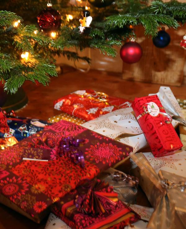 Verpackte Weihnachtsgeschenke liegen unter einem Christbaum.