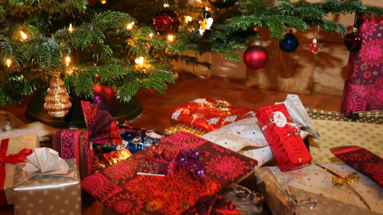 Verpackte Weihnachtsgeschenke liegen unter einem Christbaum.