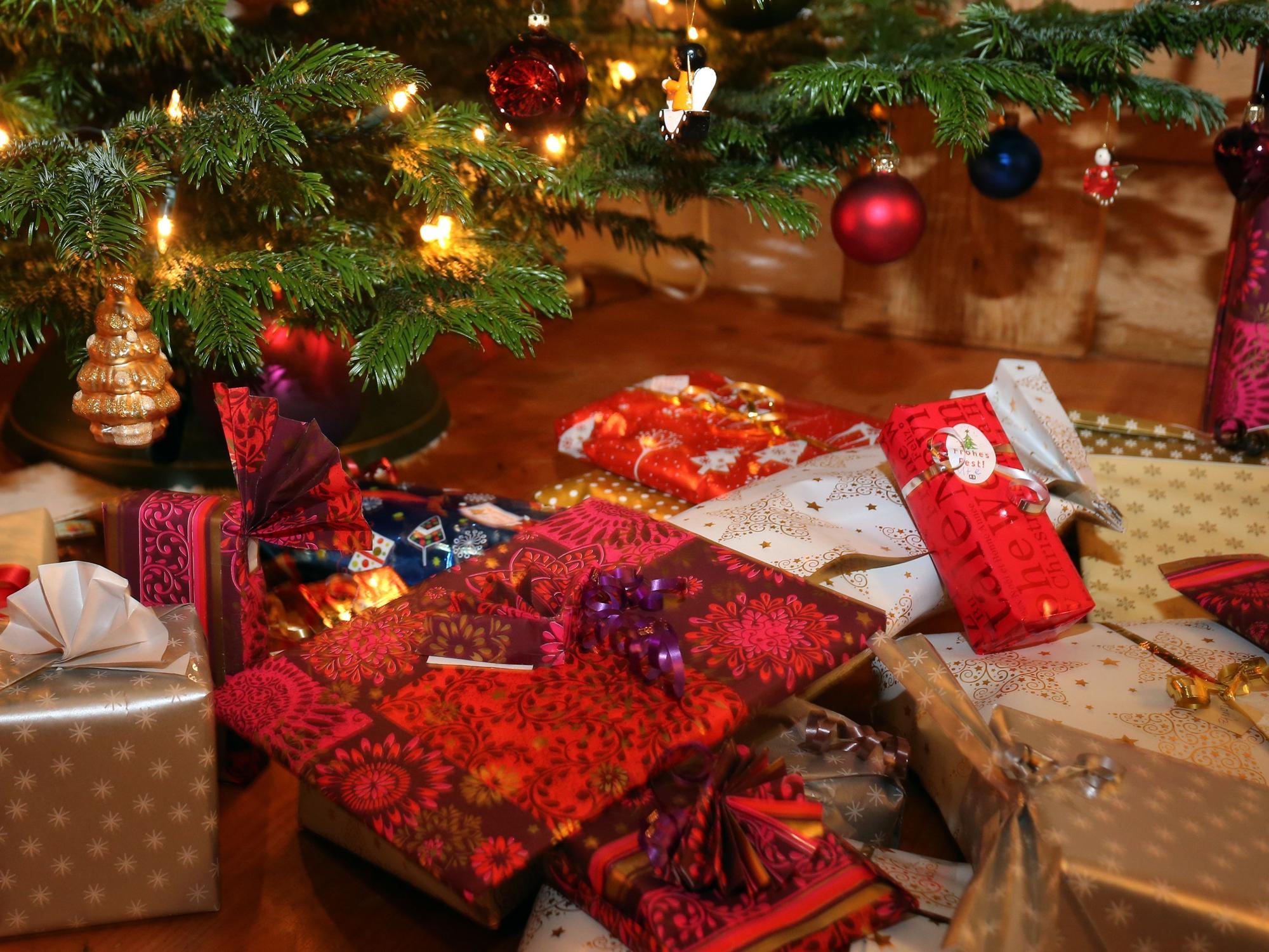 Verpackte Weihnachtsgeschenke liegen unter einem Christbaum.