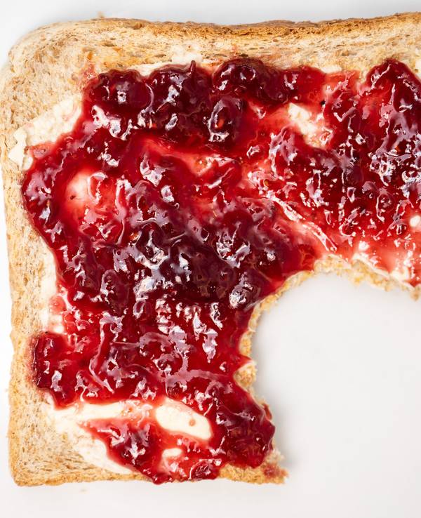 Ein Toastbrot mit Himbeermarmelade liegt auf auf einem Teller.