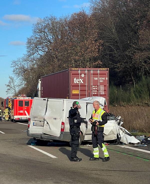 Nach einem Unfall steht ein stark beschädigter Transporter auf einer Autobahn quer zur Fahrbahn, auf dem Standstreifen ein Lkw. Einsatzfahrzeuge und -kräfte von Feuerwehr und Polizei befinden sich auf der Autobahn, ein Hubschrauber ist in der Luft.