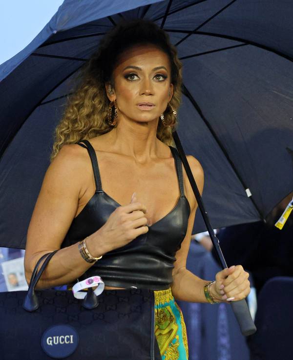Kate Abdo schützt sich mit einem Schirm vor Regen,