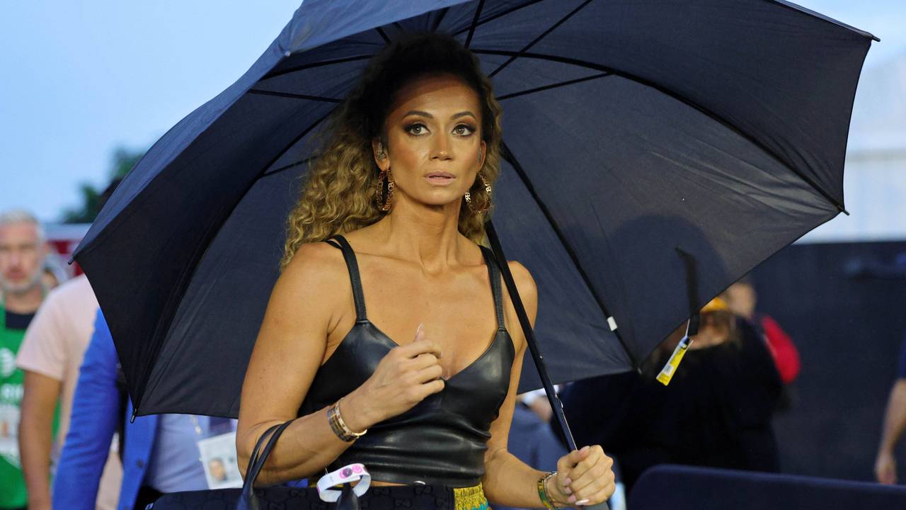 Kate Abdo schützt sich mit einem Schirm vor Regen,