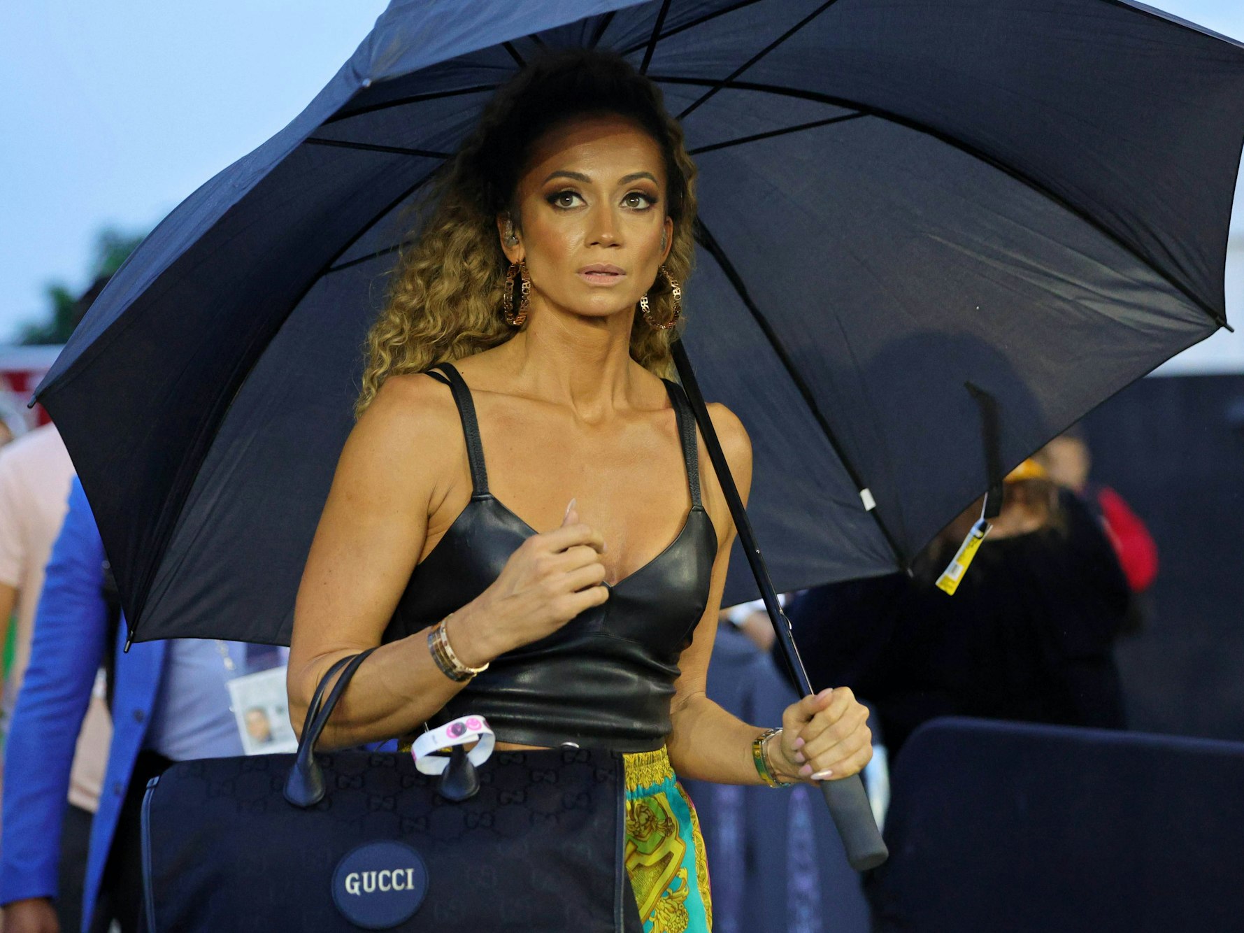 Kate Abdo schützt sich mit einem Schirm vor Regen,