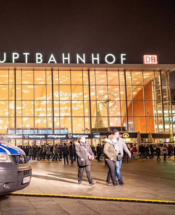 Streifenwagen der Polizei steht vor dem Kölner Hauptbahnhof, im Hintergrund sind einige Menschen zu Fuß unterwegs.