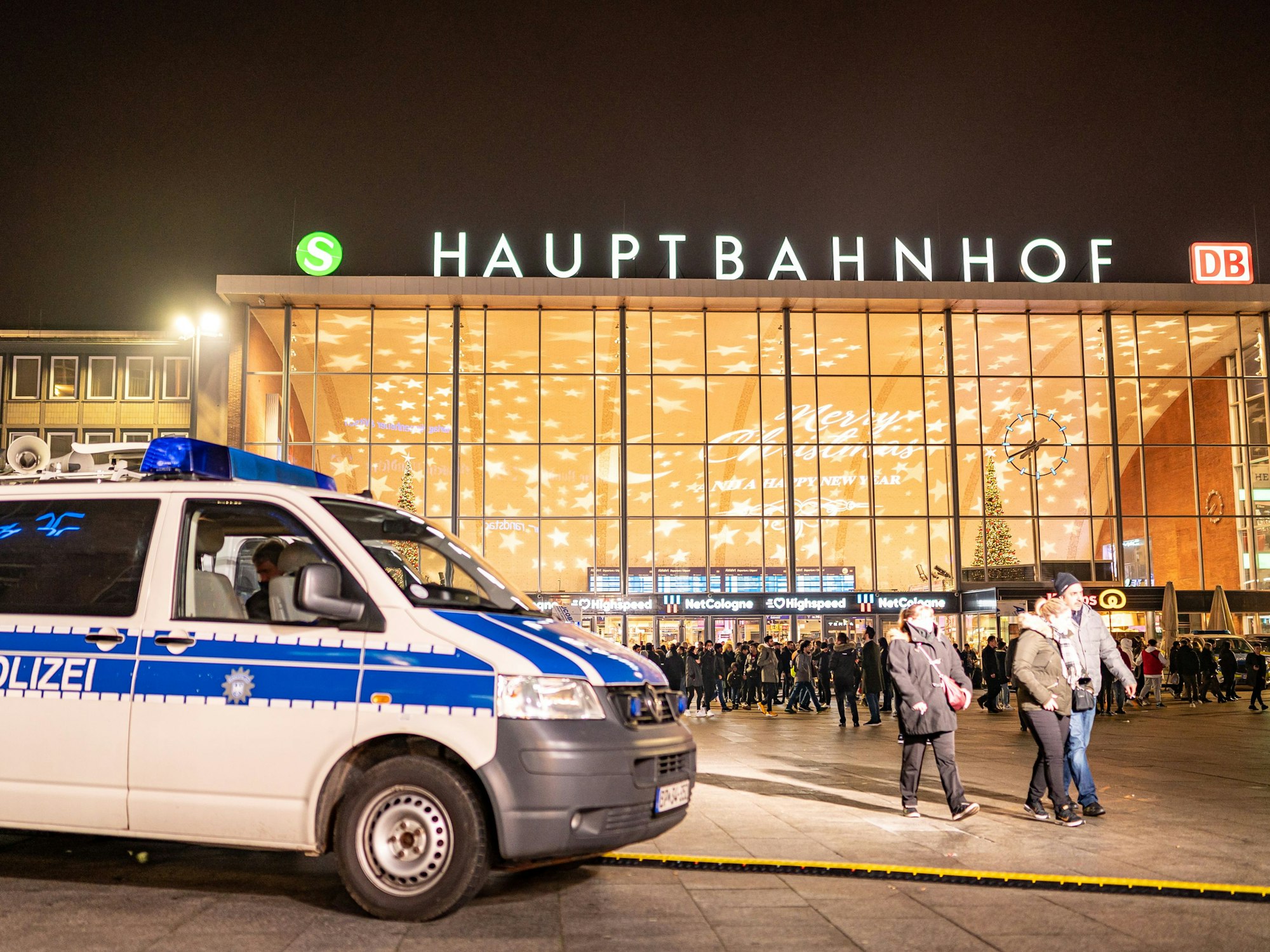 Streifenwagen der Polizei steht vor dem Kölner Hauptbahnhof, im Hintergrund sind einige Menschen zu Fuß unterwegs.