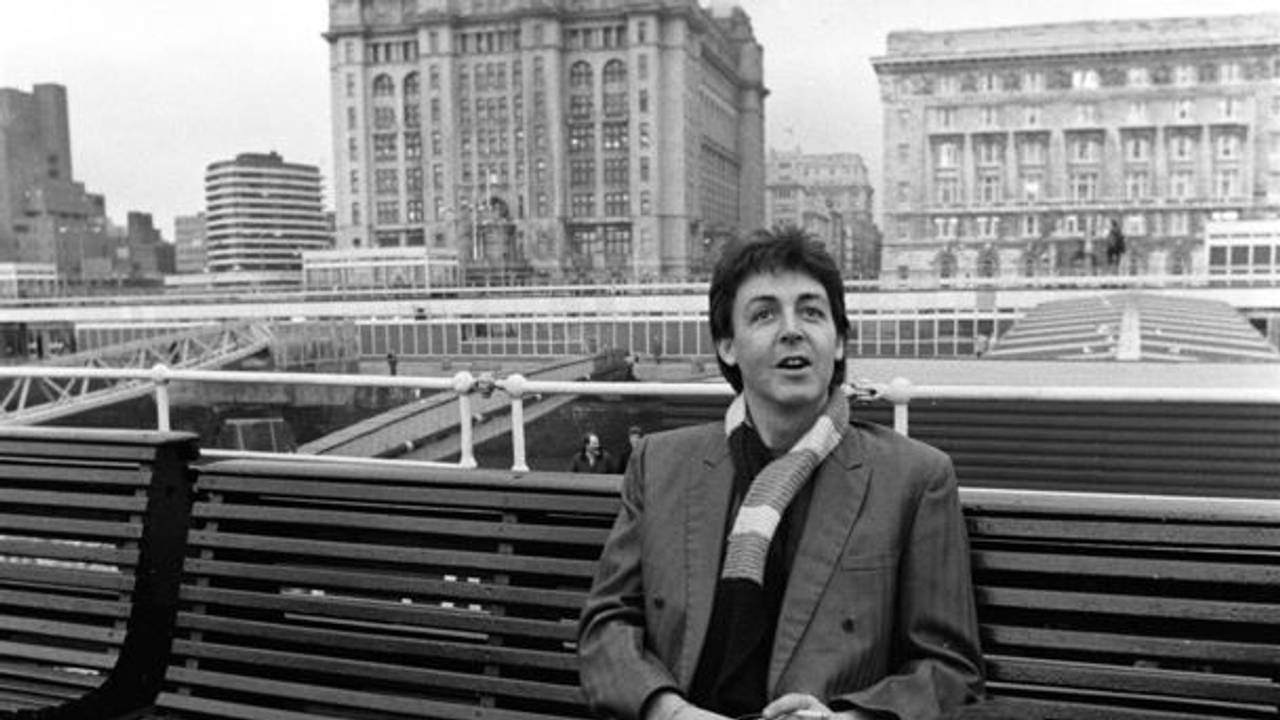 Paul McCartney sitzt auf einer Bank auf einem Schiff.