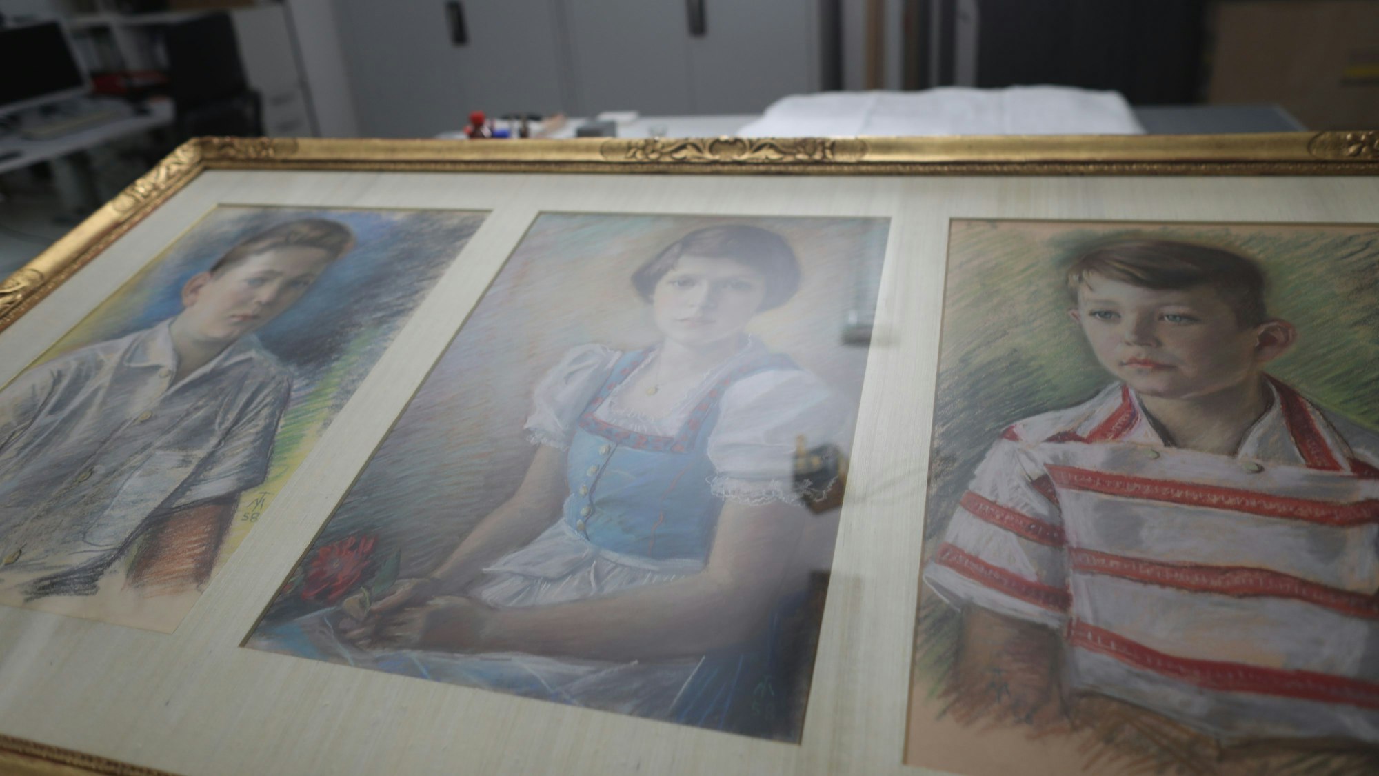 Blick auf ein Gemälde mit Porträts von drei Kindern.