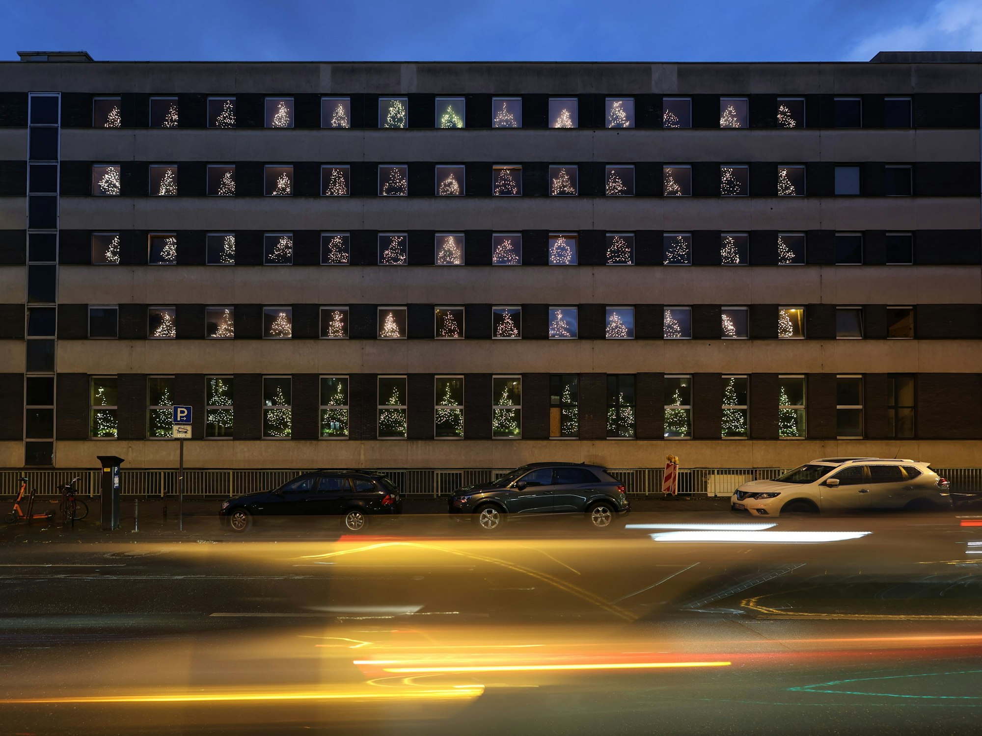 Ein Gebäude - in 65 Fenstern stehen Tannenbäume.