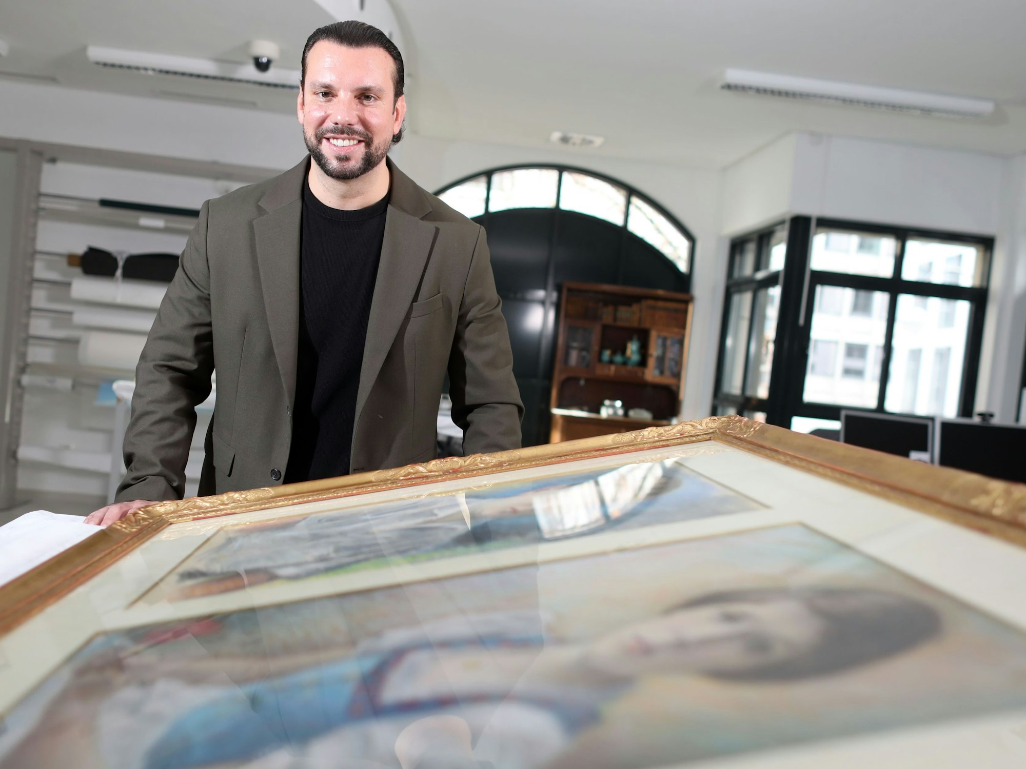 Ein Mann steht vor einem Gemälde, das auf einem Tisch liegt.