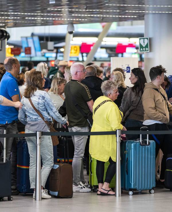 Reisende stehen in der Abflughalle des Flughafens Schiphol Schlange.