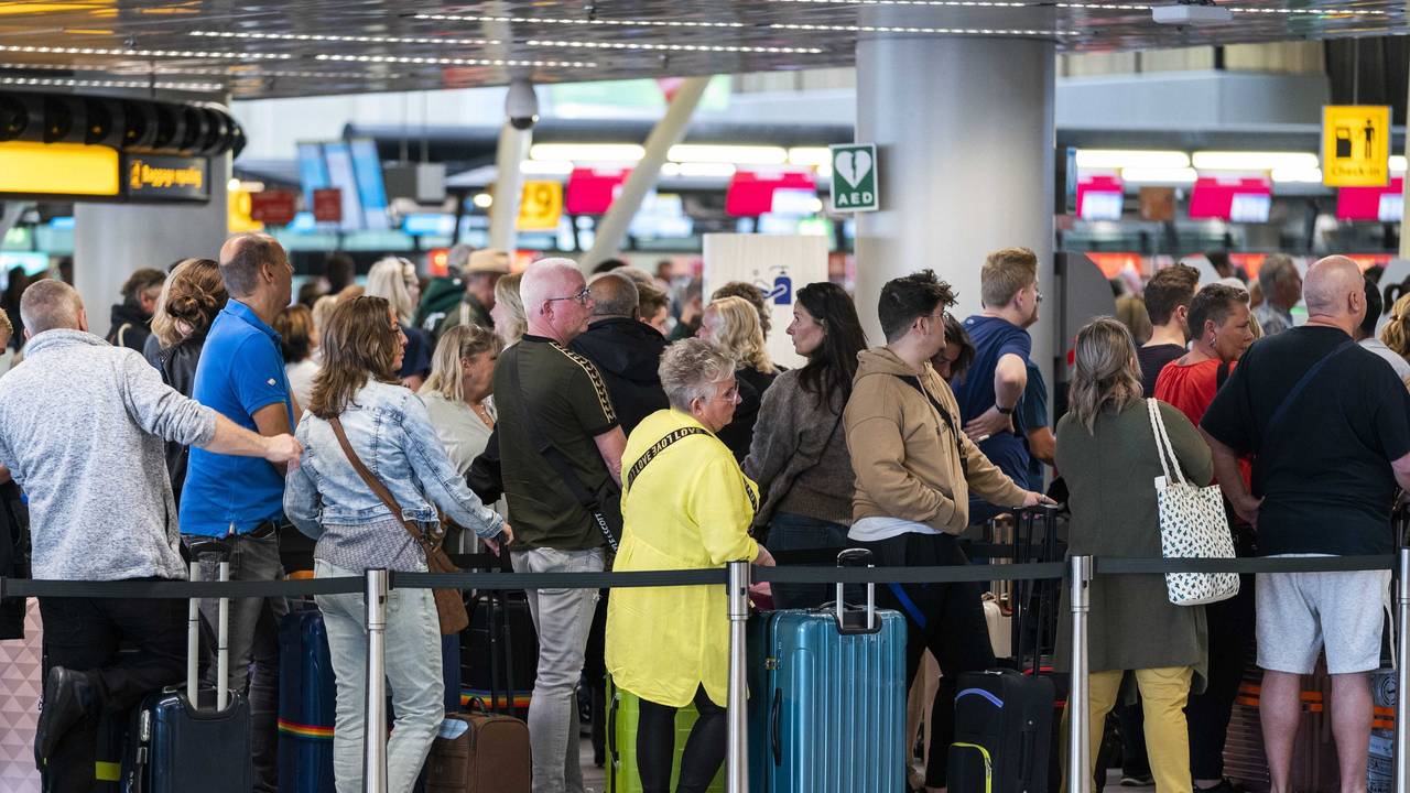 Reisende stehen in der Abflughalle des Flughafens Schiphol Schlange.
