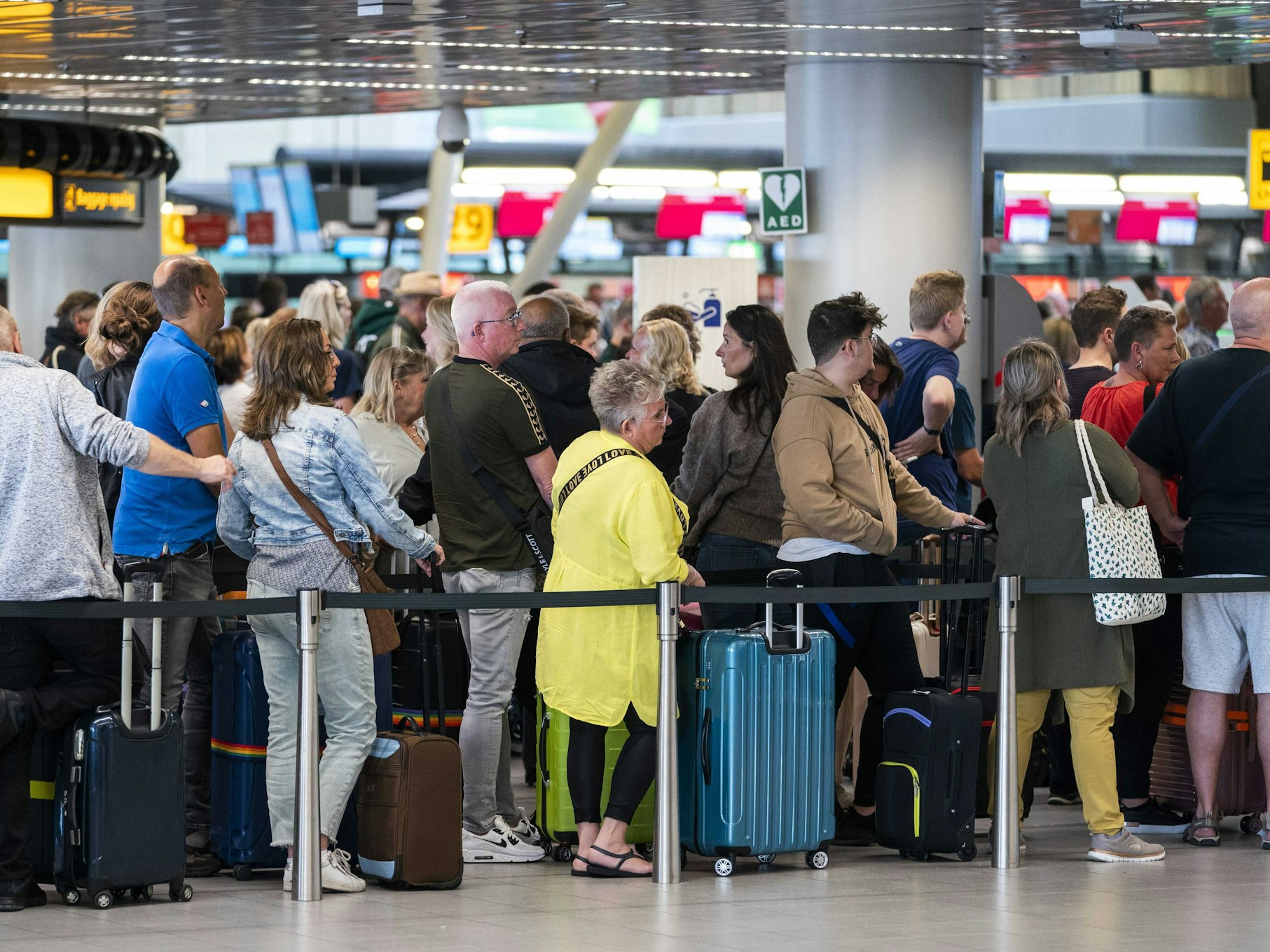 Reisende stehen in der Abflughalle des Flughafens Schiphol Schlange.