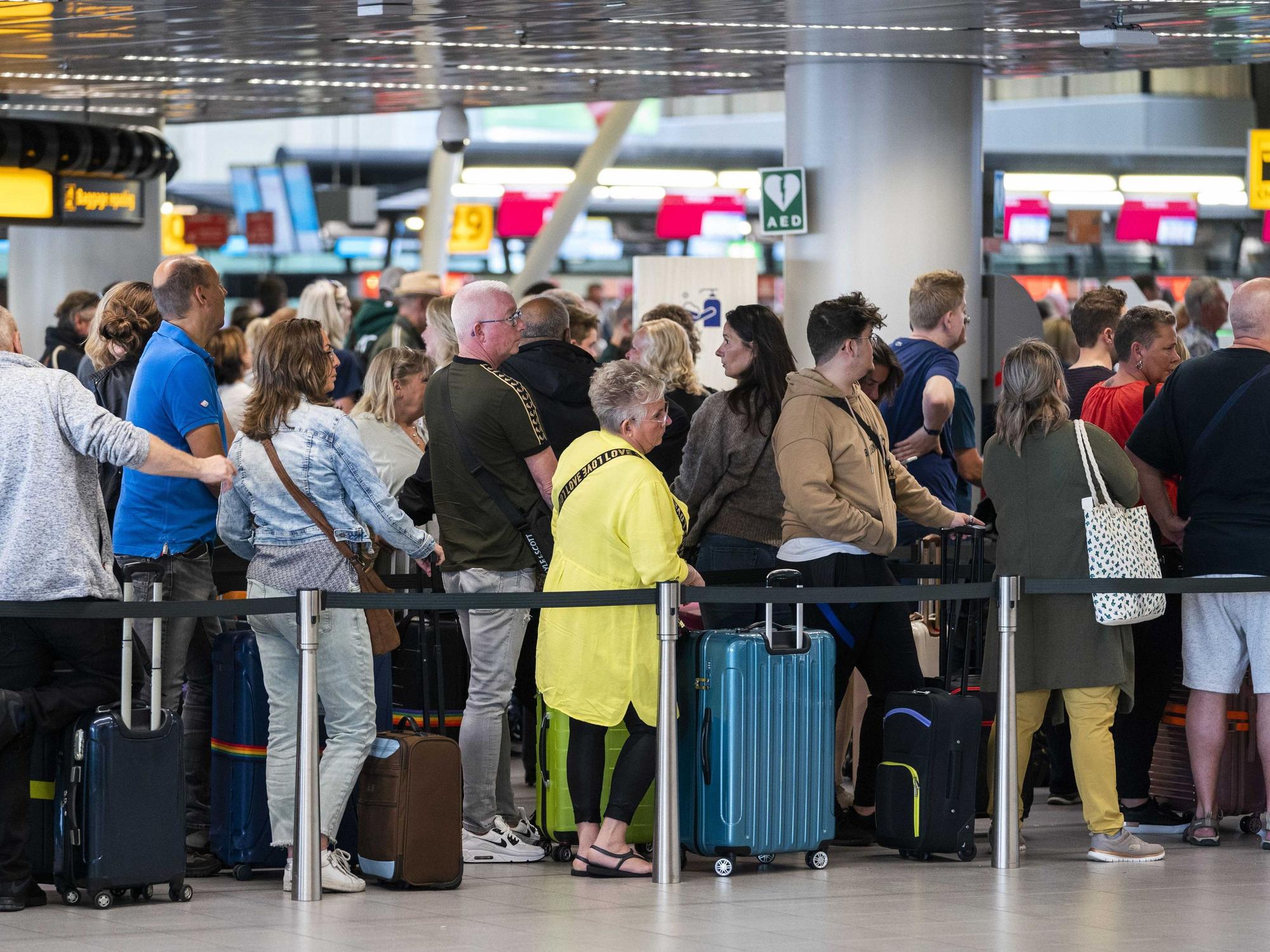 Reisende stehen in der Abflughalle des Flughafens Schiphol Schlange.