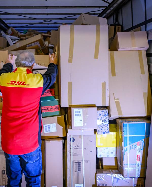 Ein Mitarbeiter bestückt im DHL-Paketzentrum den Laderaum eines Lkw mit Päckchen und Paketen.