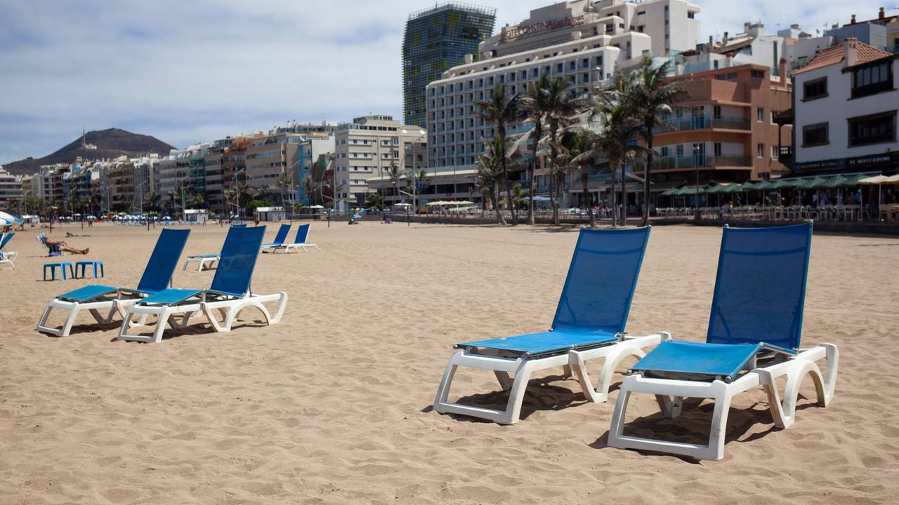 Vier Liegestühle am Strand von Las Canteras auf Gran Canaria stehen im Sand.