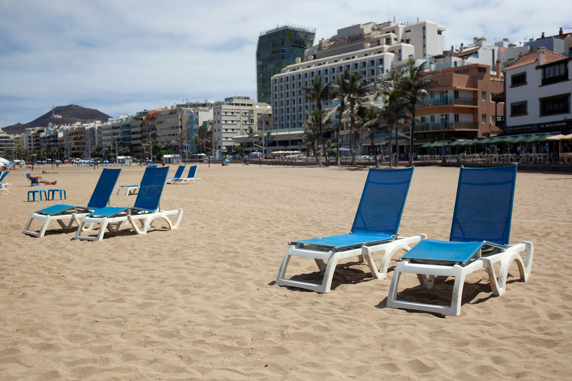 Vier Liegestühle am Strand von Las Canteras auf Gran Canaria stehen im Sand.