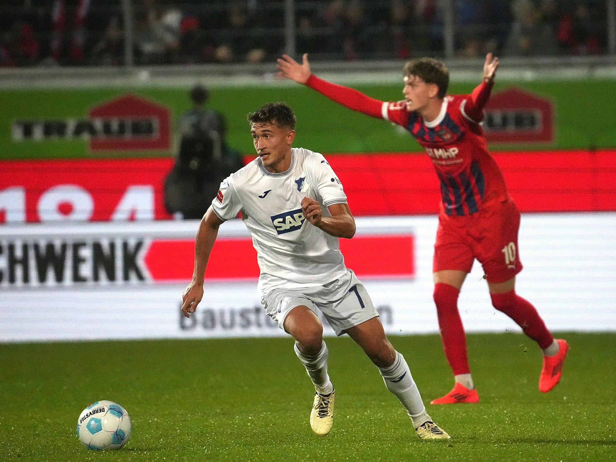 Tom Bischof dribbelt mit dem Ball, im Hintergrund lamentiert Paul Wanner.