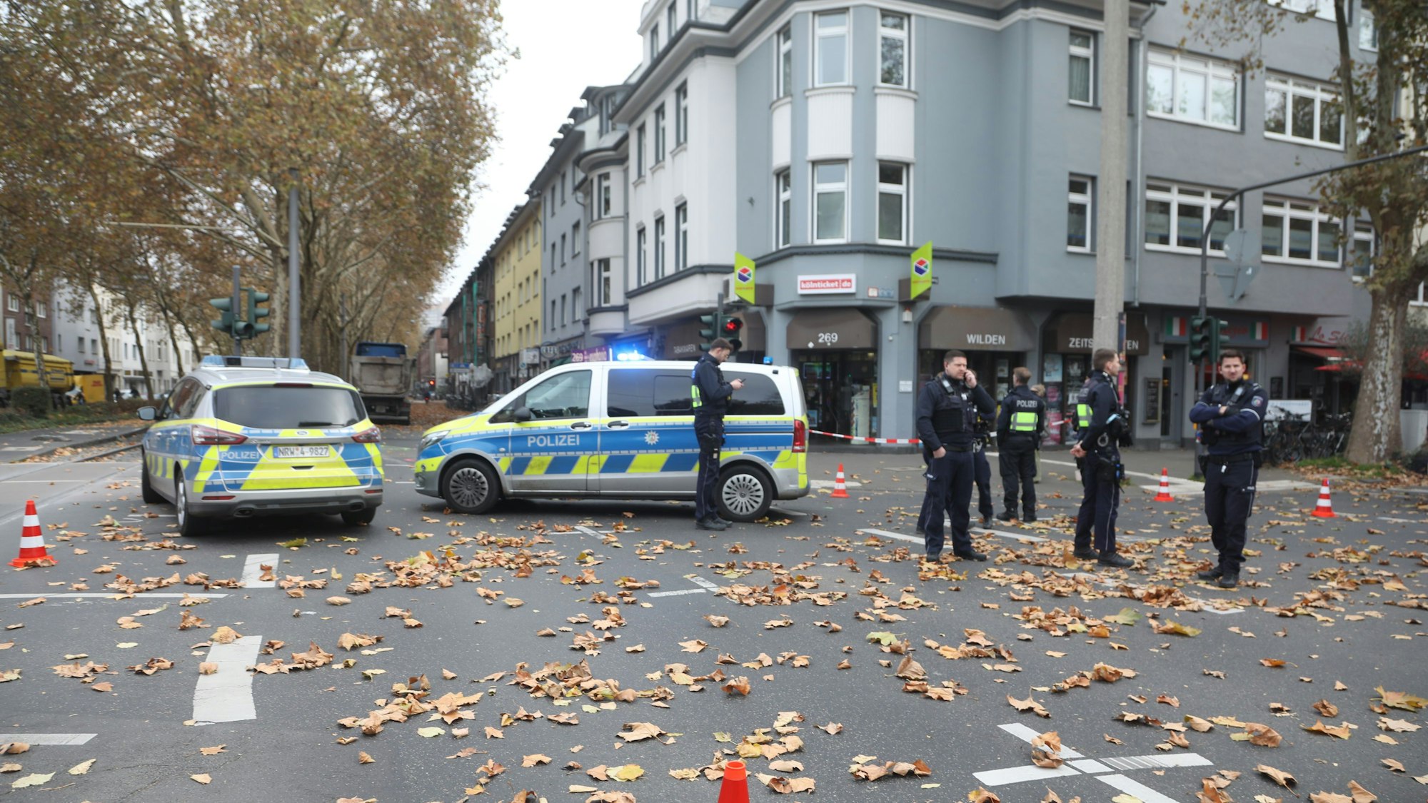 Mehrere Polizisten stehen nach einem Unfall in Köln auf einer Kreuzung.