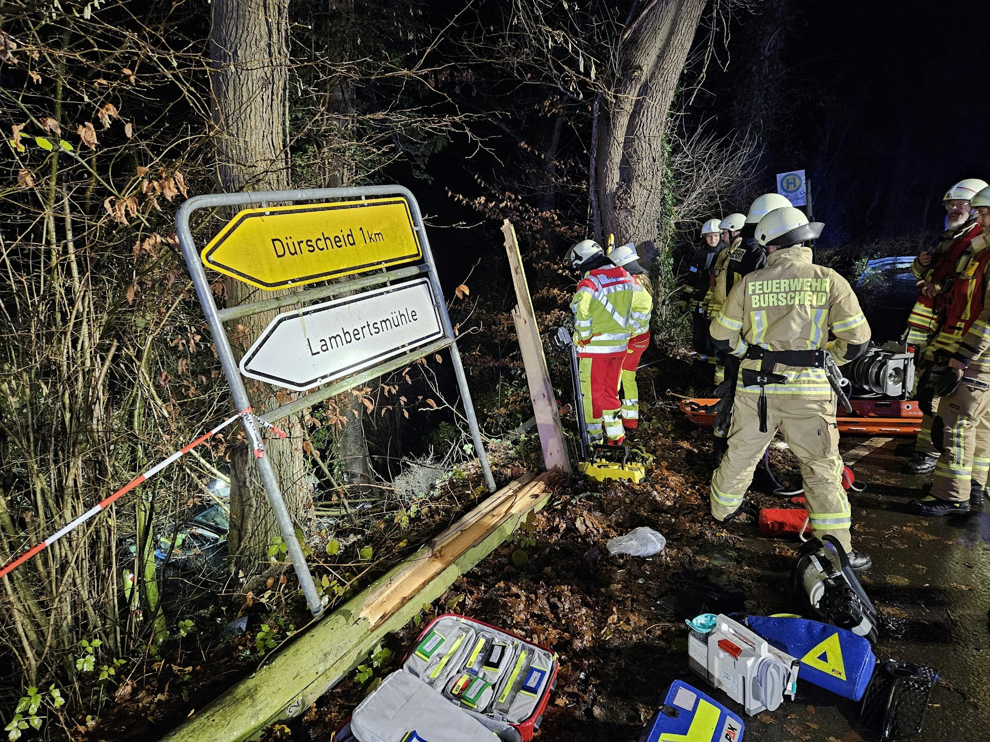 Einsatzkräfte der Feuerwehr stehen an einer Straße und bergen ein Auto.