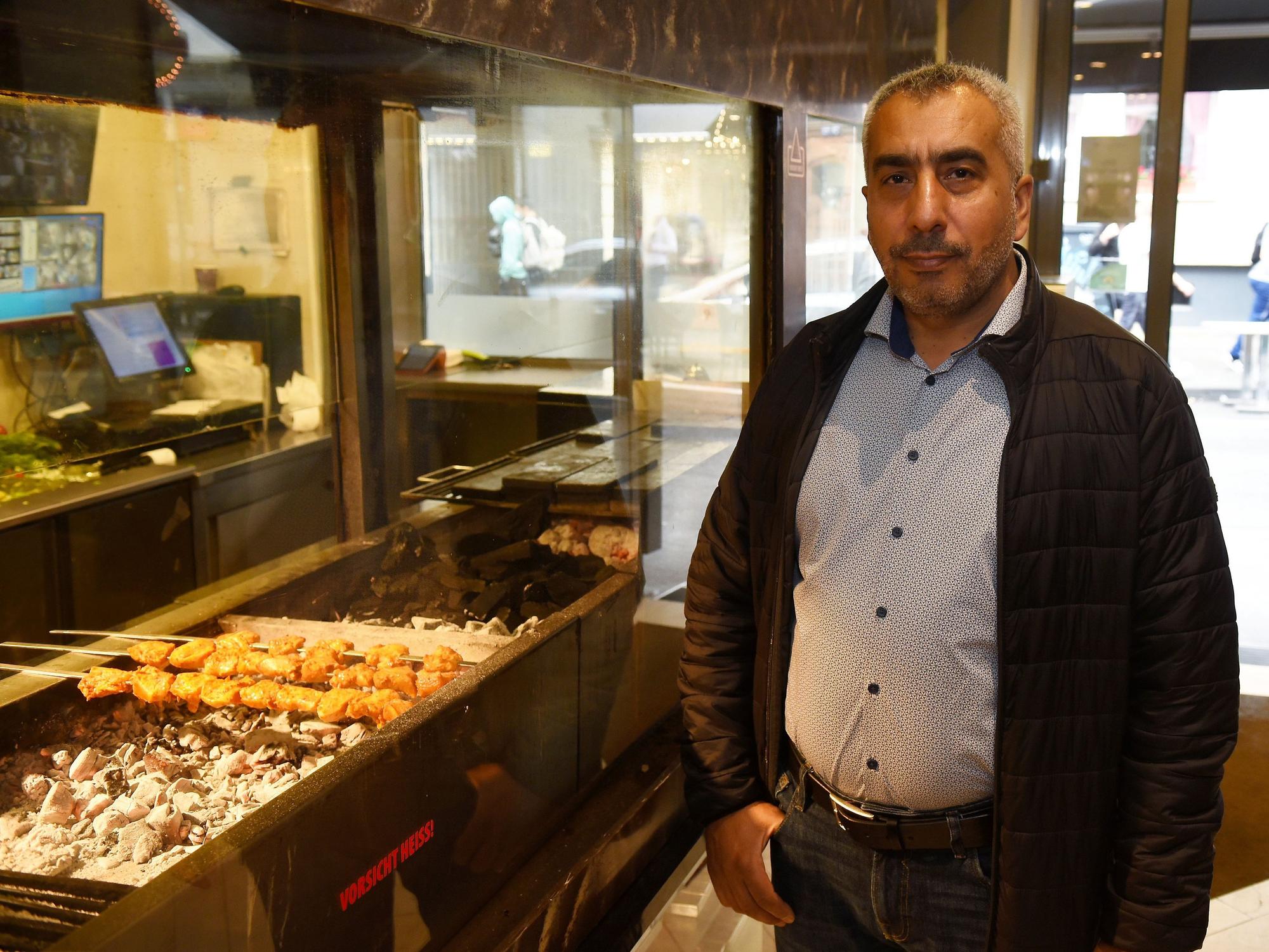 Ein Mann steht neben einem Holzkohlegrill in einem Restaurant.