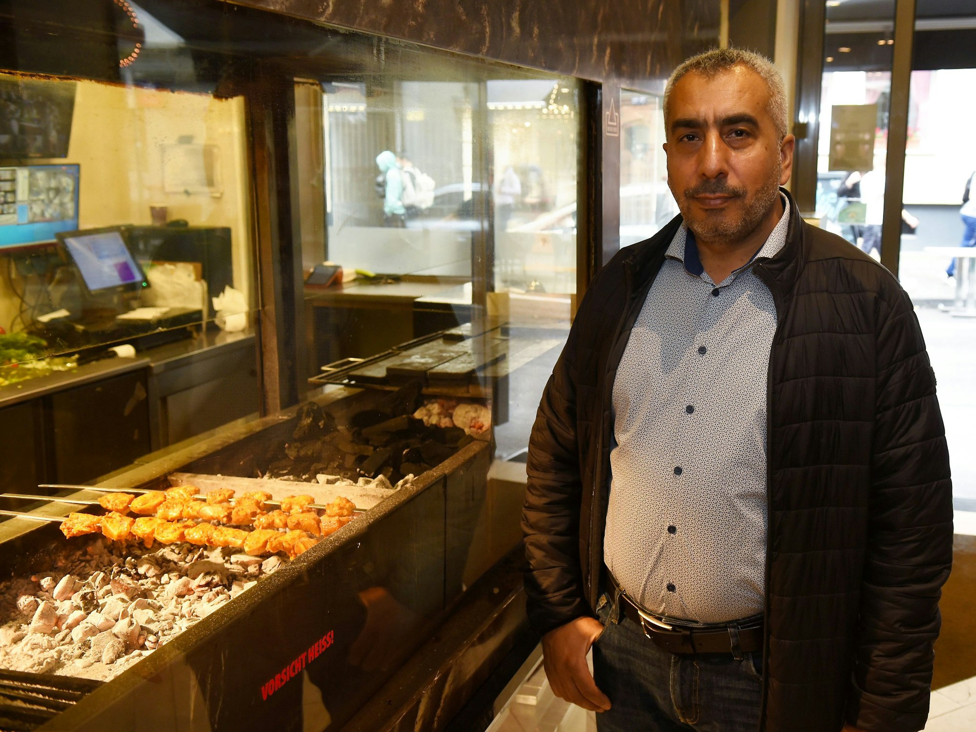 Ein Mann steht neben einem Holzkohlegrill in einem Restaurant.