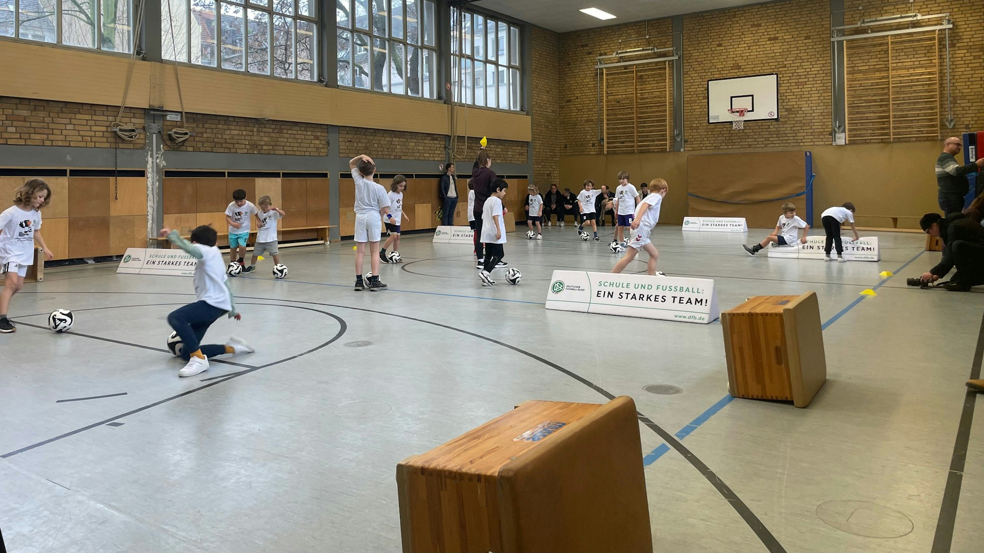 Kinder dribbeln durch die Halle.