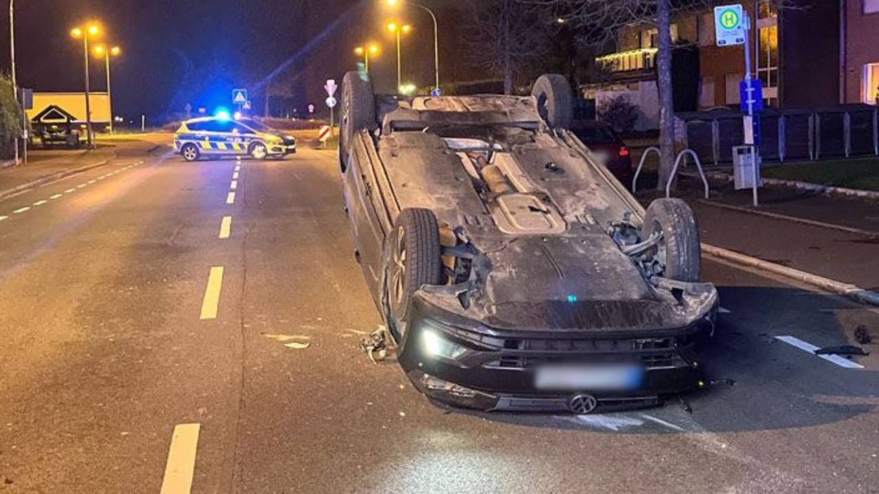 Ein Auto liegt auf dem Dach auf einer Fahrbahn.