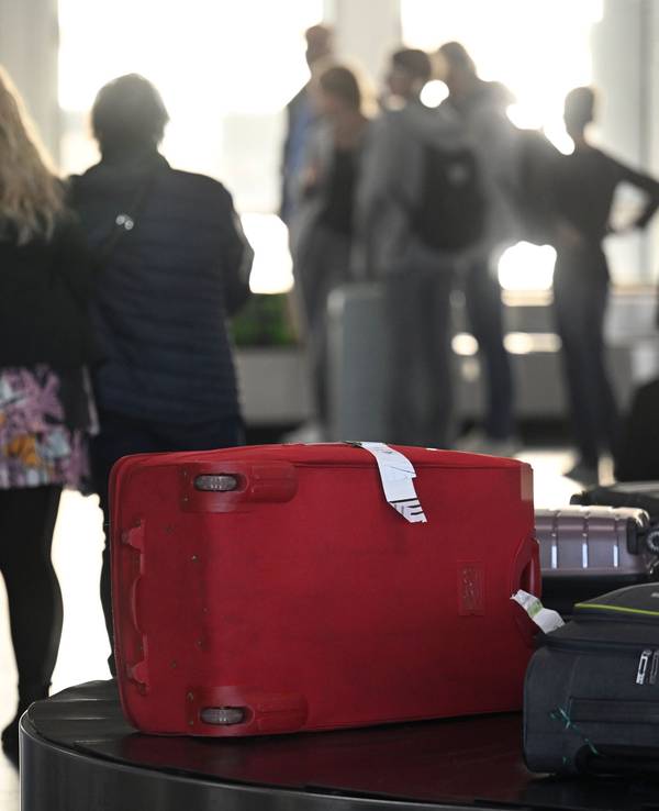 Passagiere warten nach ihrer Ankunft auf dem Konrad-Adenauer-Flughafen am Gepäckband auf ihre Koffer.